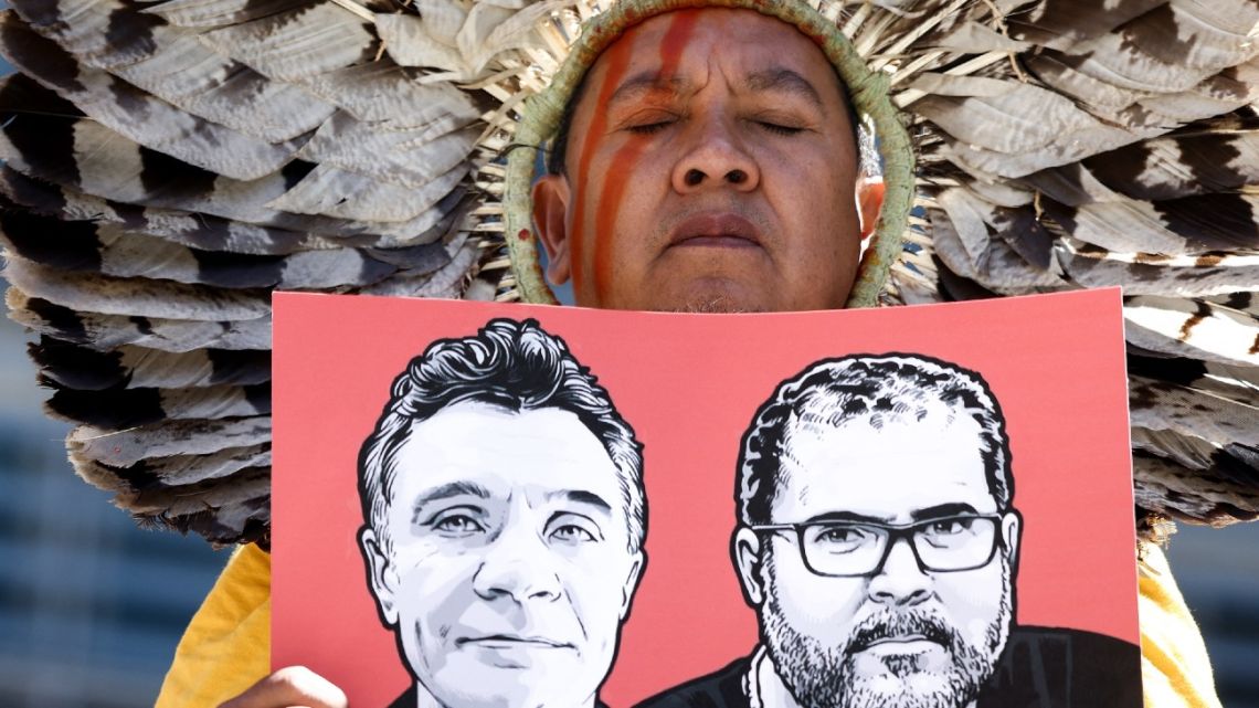 A Member of The Articulation of Indigenous Peoples of Brazil (APIB) holds the image of missing UK journalist Dom Phillips and Brazilian Indigenous affairs specialist Bruno Pereira during a protest called by activists from the climate change protest group Extinction Rebellion (XR) and members of the APIB near the European Commission building in Brussel on June 16, 2022.