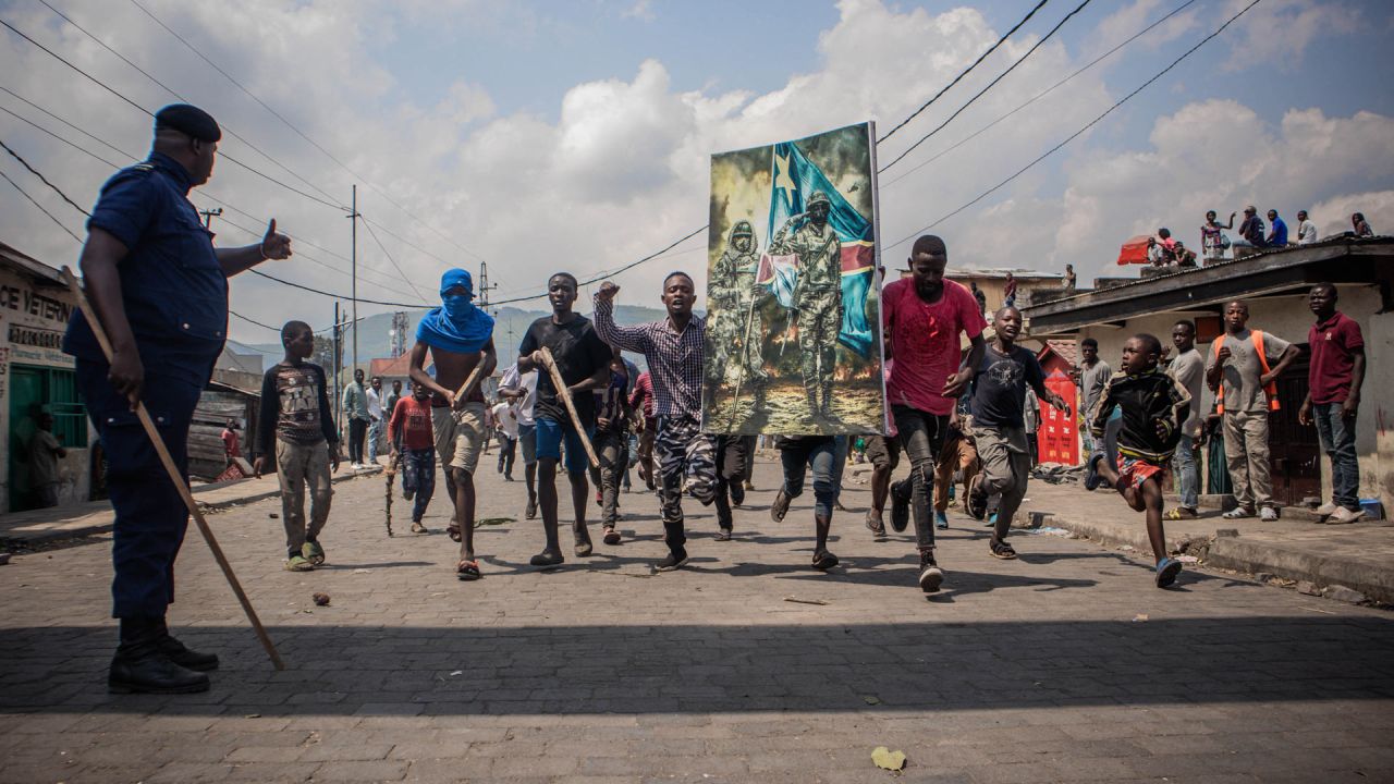 Un policía levanta el pulgar mientras los manifestantes llevan un cartel en honor a las fuerzas armadas de la República Democrática del Congo durante una protesta en Goma. - Varios miles de personas se manifestaron en Goma, en la frontera con Ruanda, en el este de la República Democrática del Congo (RDC), para denunciar la "agresión ruandesa" y expresar su apoyo al ejército congoleño, en un contexto de máxima tensión entre Kinshasa y Kigali. | Foto:Aubin Mukoni / AFP