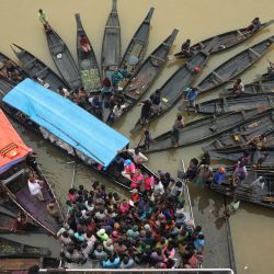 La gente se reúne para recoger ayuda alimentaria en una zona inundada tras las fuertes lluvias monzónicas en Companiganj, Bangladesh. | Foto:MARUF RAHMAN / AFP