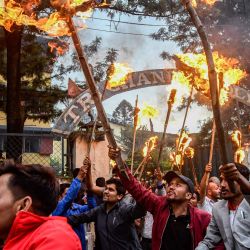 Activistas estudiantiles sostienen antorchas y gritan consignas durante una protesta por el aumento de los precios del combustible en Katmandú, Nepal. | Foto:PRAKASH MATHEMA / AFP