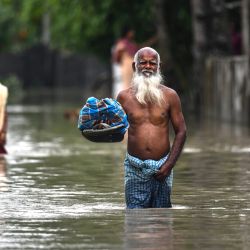 Un hombre vadea las aguas de la inundación en Rangia del distrito de Kamrup, en el estado indio de Assam. | Foto:BIJU BORO / AFP