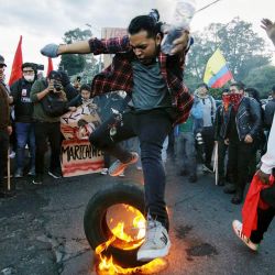 Un estudiante universitario salta sobre un neumático en llamas durante una manifestación contra el gobierno del presidente Guillermo Lasso en el marco de las protestas lideradas por los indígenas, en el centro de Quito, Ecuador. | Foto:Verónica Lombeida / AFP