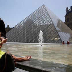 Una persona se sienta cerca de una fuente frente a la Pirámide del Louvre en París, mientras una ola de calor se extiende por gran parte de Francia y Europa. | Foto:STEFANO RELLANDINI / AFP