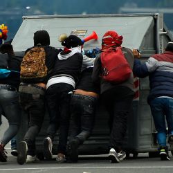 Manifestantes mueven un contenedor de basura durante los enfrentamientos con la policía antidisturbios en la zona del parque El Arbolito en Quito, en el décimo día consecutivo de protestas lideradas por indígenas contra el gobierno ecuatoriano. | Foto:RODRIGO BUENDIA / AFP