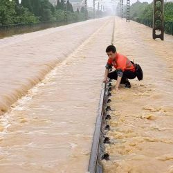 Un empleado ferroviario comprueba una vía férrea inundada tras las fuertes lluvias en Shangrao, en la provincia central china de Jiangxi. | Foto:AFP