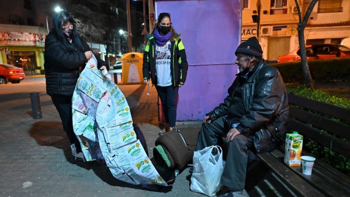 Members of the Dando Una Mano NGO assist the homeless, providing food and blankets made out of recycled milk sachets made by volunteers of the La Sachetera group, in San Fernando, Buenos Aires Province on June 20, 2022. 