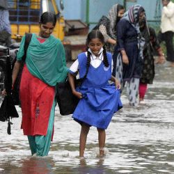 Una mujer junto con una niña de la escuela caminan por un camino inundado luego de una fuerte lluvia en Hyderabad. Noah SEELAM / AFP | Foto:AFP