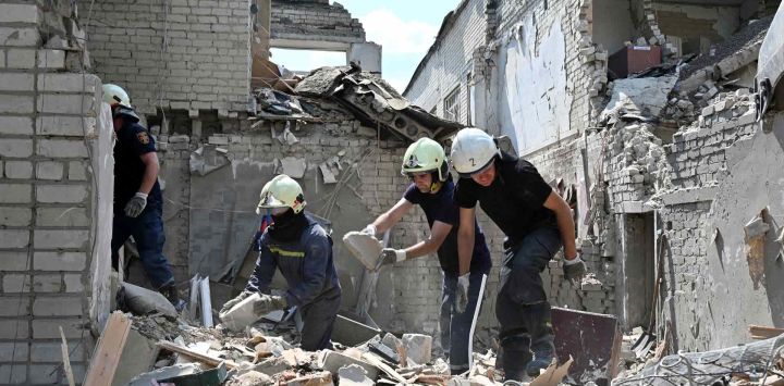 Los rescatistas trabajan en las ruinas de un edificio escolar, parcialmente destruido por dos cohetes en la ciudad ucraniana de Kharkiv. SERGEY BOBOK / AFP