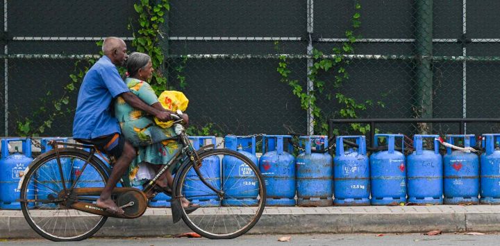 Un ciclista vende cilindros de gas licuado de petróleo (GLP) colocados por personas que hacen cola para comprar combustible en Galle. Ishara S. KODIKARA / AFP.
