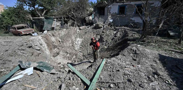 Un trabajador se para en un cráter frente a una casa gravemente dañada en una zona residencial de Kramatorsk, el día después de un ataque con cohetes rusos. Genya SAVILOV / AFP.