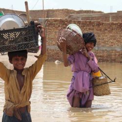 Niños que cargan artículos para el hogar caminan por un área inundada después de una lluvia monzónica en Quetta. Banaras KHAN / AFP. | Foto:AFP