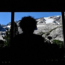 Una persona mira desde la ventana del refugio Castiglioni el glaciar Punta Rocca que se derrumbó cerca de Canazei, en la montaña de la Marmolada. Tiziana FABI / AFP. | Foto:AFP