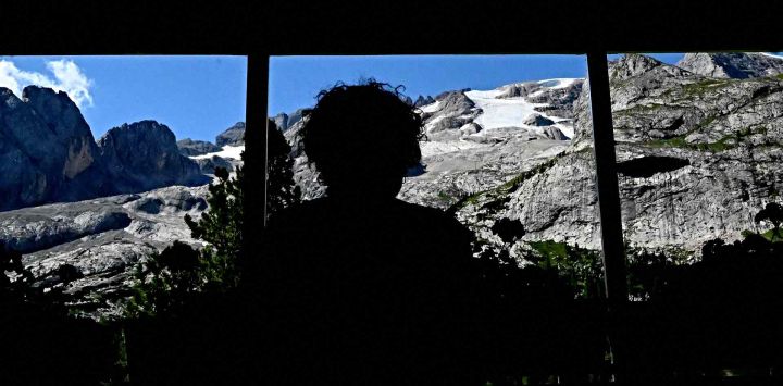 Una persona mira desde la ventana del refugio Castiglioni el glaciar Punta Rocca que se derrumbó cerca de Canazei, en la montaña de la Marmolada. Tiziana FABI / AFP.