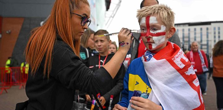 Un joven aficionado de Inglaterra se pinta la cara cuando llega al partido de fútbol del Grupo A de la Eurocopa Femenina de la UEFA 2022 entre Inglaterra y Austria en Old Trafford en Manchester, noroeste de Inglaterra. MIHAILESCU / AFP.
