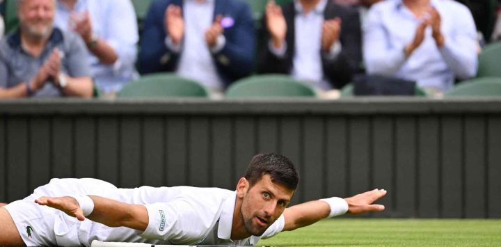 El serbio Novak Djokovic reacciona mientras se acuesta en el césped durante su partido de tenis de cuartos de final de individuales masculinos en el Campeonato de Wimbledon 2022. SEBASTIEN BOZON / AFP.