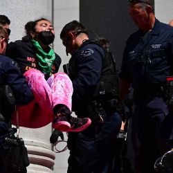 La policía interviene para arrestar a los activistas por el derecho al aborto que se manifiestan encadenados en medio de salpicaduras de sangre falsa en los escalones del Ayuntamiento en Los Ángeles, California. Frederic J. BROWN / AFP. | Foto:AFP
