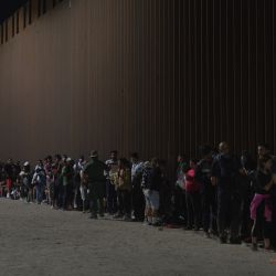 Migrantes en fila mientras esperan ser procesados por la Patrulla Fronteriza de Estados Unidos tras cruzar ilegalmente la frontera entre Estados Unidos y México en Yuma, Arizona. | Foto:Allison Dinner / AFP