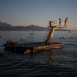 Los bañistas se lanzan desde una plataforma en el lago Lemán, en Lutry, cerca de Lausana, Suiza. | Foto:FABRICE COFFRINI / AFP