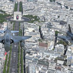 Una vista aérea muestra aviones de combate Mirage 2000 realizando un sobrevuelo durante el desfile militar del Día de la Bastilla sobre la avenida de los Campos Elíseos en París. | Foto:CHRISTOPHE SIMON / AFP