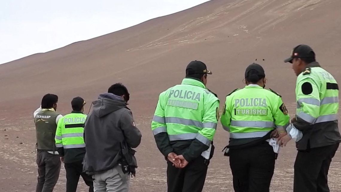 In this frame grab from a video courtesy of the Peruvian Ministry of Culture obtained on July 12, 2022, police officers are pictured near the Paracas Candelabra, which was damaged by intruders, in Paracas, Peru. The famous Paracas Candelabra, a geoglyph of about 2,500 years old on a hill facing the sea in southern Peru, was damaged by intruders who walked on it this weekend, the Ministry of Culture reported.