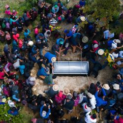 En esta vista aérea, indígenas entierran el ataúd de Melvin Guachiac, un adolescente guatemalteco de 13 años que murió dentro de un camión tractor en Texas después de cruzar desde México, en el cementerio municipal de la aldea Tzucubal en Nahuala, Guatemala. | Foto:CARLOS ALONZO / AFP