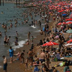 Los bañistas se sientan al sol en la playa y reman en el mar en Brighton, al sur de Inglaterra. | Foto:DANIEL LEAL / AFP