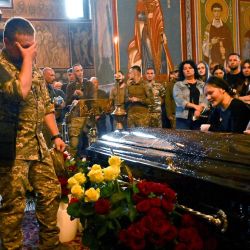 Militares ucranianos y familiares lloran ante el féretro del oficial apodado Fanat durante su funeral en Kiev. | Foto:SERGEI SUPINSKY / AFP