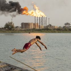 Un iraquí se sumerge en el río Shatt al-Arab frente al yacimiento petrolífero de Nahr Bin Omar, en la provincia meridional iraquí de Basora. | Foto:HUSSEIN FALEH / AFP