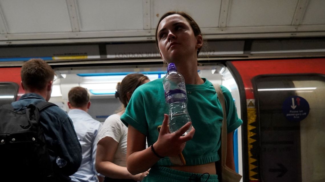 A commuter carries a bottle of water as they exit the carriage of a London Underground tube train in central London, on July 19, 2022 as the country experiences an extreme heat wave. Britain on Tuesday recorded its first ever temperature exceeding 40 degrees Celsius (104 degrees Fahrenheit), with the mercury provisionally registering 40.2C at Heathrow Airport, the country's meteorological agency the Met Office said.