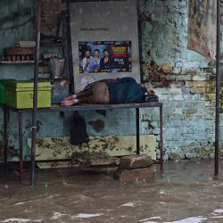 Un vendedor ambulante se echa una siesta en una calle inundada tras las fuertes lluvias en Ahmedabad, India. | Foto:SAM PANTHAKY / AFP