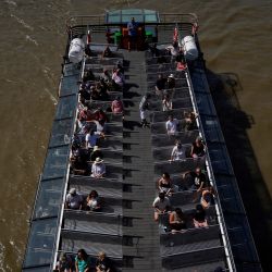 Pasajeros sentados en un barco turístico mientras navega por el río Támesis en el centro de Londres. | Foto:NIKLAS HALLE'N / AFP