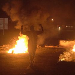 Un manifestante levanta las manos frente a neumáticos en llamas durante una protesta contra los precios de los combustibles en Santiago, provincia de Veraguas, Panamá. | Foto:Mauricio Valenzuela / AFP