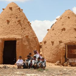 Abdulaziz al-Oqab y sus sobrinos, huérfanos tras la explosión de una mina terrestre bajo una camioneta, matando a varios miembros de la familia, se sientan frente a las tradicionales chozas de barro tipo colmena en un pueblo de la provincia central siria de Hama. | Foto:LOUAI BESHARA / AFP