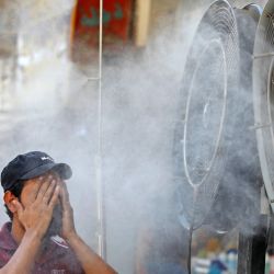 Un hombre iraquí se refresca frente a unos ventiladores en medio de una ola de calor en el centro de Bagdad, Irak. | Foto:AHMAD AL-RUBAYE / AFP