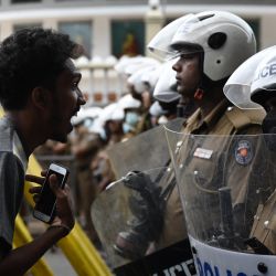 Un manifestante interactúa con el personal de las fuerzas especiales de la policía que hacen guardia bloqueando una carretera mientras los manifestantes participan en una marcha de protesta contra el presidente de Sri Lanka, Ranil Wickremesinghe. | Foto:ARUN SANKAR / AFP