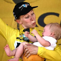 La ciclista holandesa del equipo DSM, Lorena Wiebes, con su hijo en brazos, celebra su maillot amarillo de líder de la general en el podio al final de la primera etapa de la nueva edición del Tour de Francia femenino, de 81,6 km entre la Tour Eiffel y los Campos Elíseos, en París. | Foto:JEFF PACHOUD / AFP