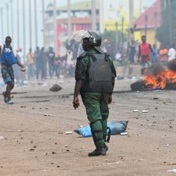 Un agente de policía observa cómo los manifestantes bloquean las carreteras y lanzan piedras en Conakry después de que las autoridades impidieran a los partidarios del partido de la oposición, el Frente Nacional para la Defensa de la Constitución (FNDC), reunirse en las calles para una marcha pacífica. | Foto:CELLOU BINANI / AFP