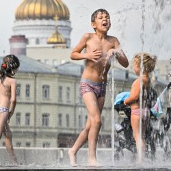 Unos niños se refrescan en una fuente en el centro de Moscú frente a la catedral del Cristo Salvador. | Foto:ALEXANDER NEMENOV / AFP