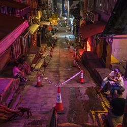 Esta foto muestra a personas sentadas en una calle acordonada por la policía con bares y restaurantes cerrados debido a las restricciones del coronavirus Covid-19 en Hong Kong. | Foto:DALE DE LA REY / AFP