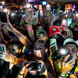 Los fans sostienen las linternas de sus teléfonos inteligentes mientras el músico puertorriqueño Mora actúa en Miami, Florida. | Foto:CHANDAN KHANNA / AFP