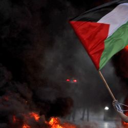 Un manifestante enmascarado agita una bandera palestina cerca de un neumático incendiado durante los enfrentamientos con las fuerzas israelíes tras una protesta para denunciar la "marcha de la bandera" nacionalista anual a través de Jerusalén, cerca del asentamiento de Beit El en la entrada norte de la ciudad de Ramala en la Cisjordania ocupada. | Foto:ABBAS MOMANI / AFP
