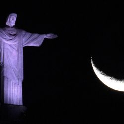 La luna creciente se ve junto a la estatua del Cristo Redentor en Río de Janeiro, Brasil. | Foto:MAURO PIMENTEL / AFP