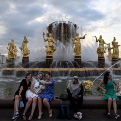 Mujeres sentadas en la fuente Druzhba Narodov (Amistad de las Naciones) en el Centro de Exposiciones toda Rusia en Moscú. | Foto:KIRILL KUDRYAVTSEV / AFP