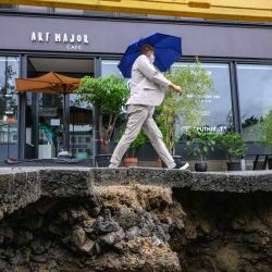 Un hombre pasa junto a un pavimento dañado en Seúl, después de que las lluvias récord causaran graves inundaciones, con al menos siete muertos y siete más desaparecidos, dijeron las autoridades. Anthony WALLACE / AFP. | Foto:AFP