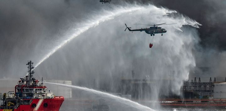 El buque de extinción de incendios mexicano "Bourbon Artabaze" y los helicópteros luchan para contener el incendio de varios días en un depósito de combustible provocado por un rayo en Matanzas, Cuba. Yamil LAGE / AFP.
