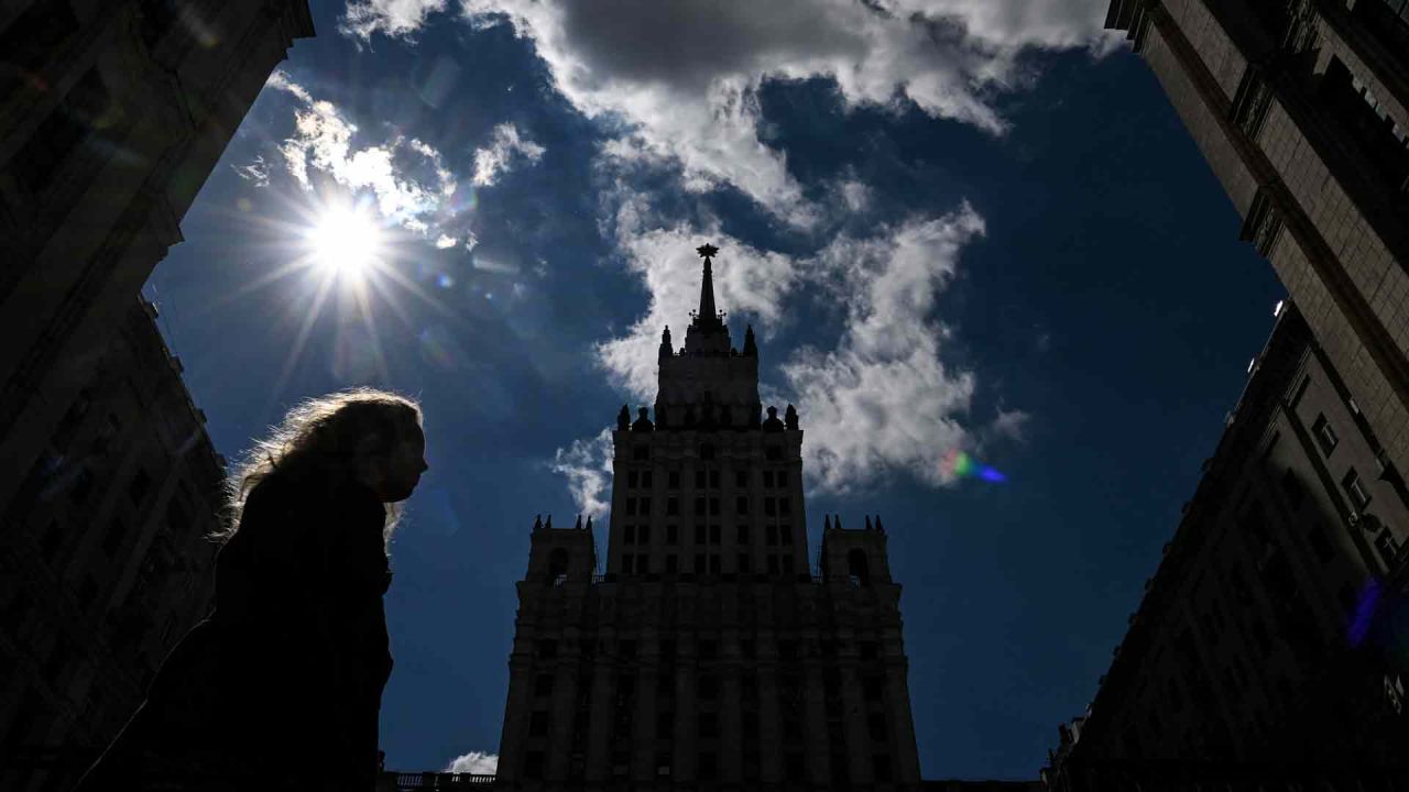 Una mujer pasa junto a un rascacielos de la era de Stalin visto en silueta durante un día soleado en el centro de Moscú. Kirill KUDRYAVTSEV / AFP. | Foto:AFP