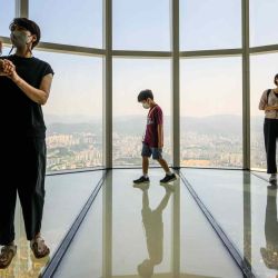 Los visitantes posan para selfies mientras un niño camina en la plataforma de observación en Lotte World Tower Seoul Sky en Seúl. Anthony WALLACE / AFP. | Foto:AFP