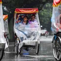 Los turistas realizan un recorrido por la ciudad en un ciclo durante la lluvia, en el centro de Hanoi. Nhac NGUYEN / AFP. | Foto:AFP