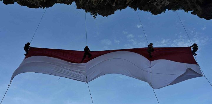 Un grupo de estudiantes universitarios despliega una gran bandera nacional antes de las celebraciones para conmemorar el 77º Día de la Independencia de Indonesia, en la playa de Lhoknga, en la provincia de Aceh. CHAIDEER MAHYUDDIN / AFP.