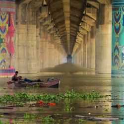 Los hombres descansan en un bote en el río Ganges desbordado bajo el puente Shastri en Allahabad, cuando los niveles de agua de los ríos Ganges y Yamuna aumentaron tras las lluvias monzónicas. SANJAY KANOJIA / AFP. | Foto:AFP